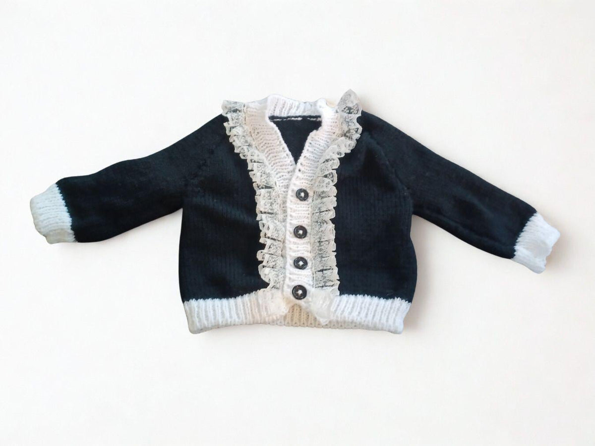 Black cardigan with white trim and lace edging.