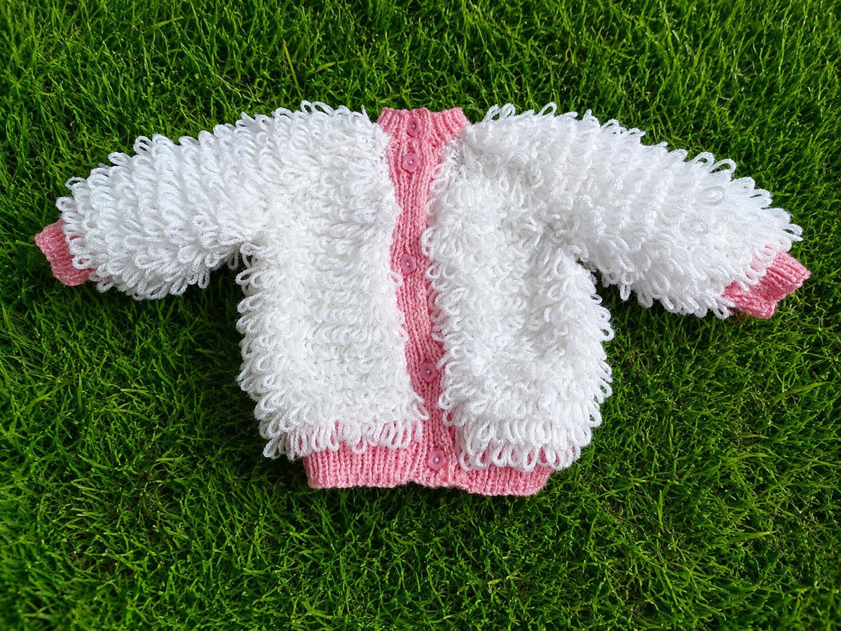 A white loopy-knit cardigan with pink edging, soft texture, and delicate pink buttons